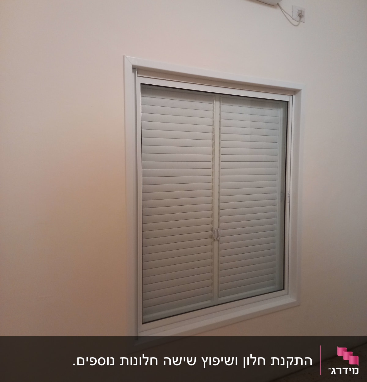 חלון עם תריסי אלומיניום סגורים במסגרת לבנה